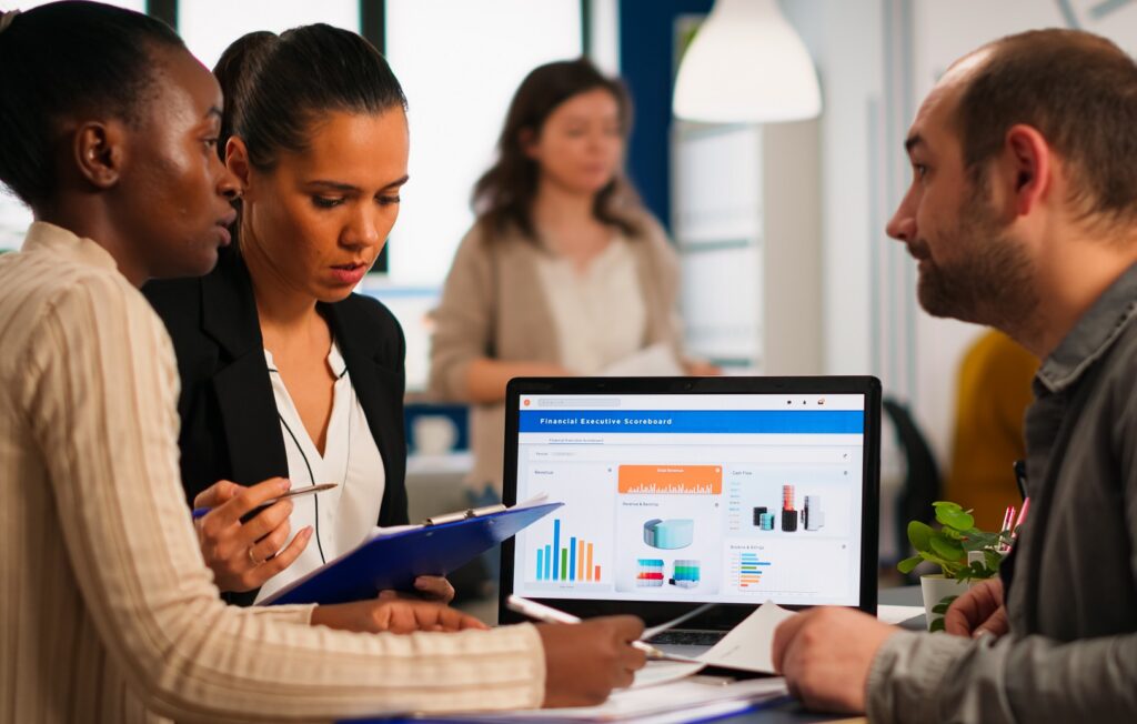 busy diverse employees analysing annual financial statistics sitting in front of laptop
